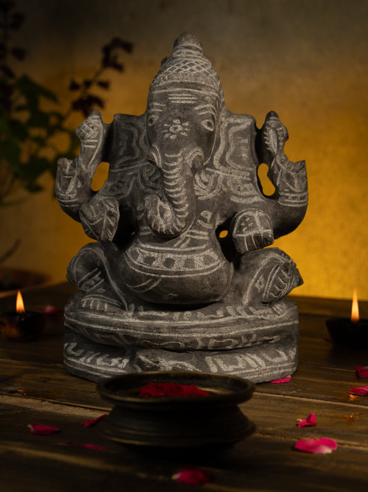 Black Stone Vinayagar Idol in Traditional Pooja Setup with Diyas, Rose Petals, and Tulsi Plant for Home Decor or Vastu Placement.
